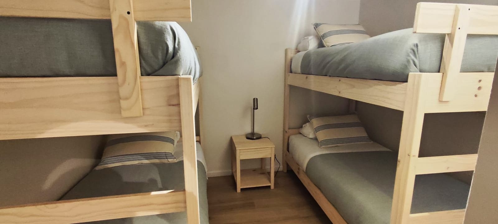 Una camera con un letto a castello, un comodino e una lampada.