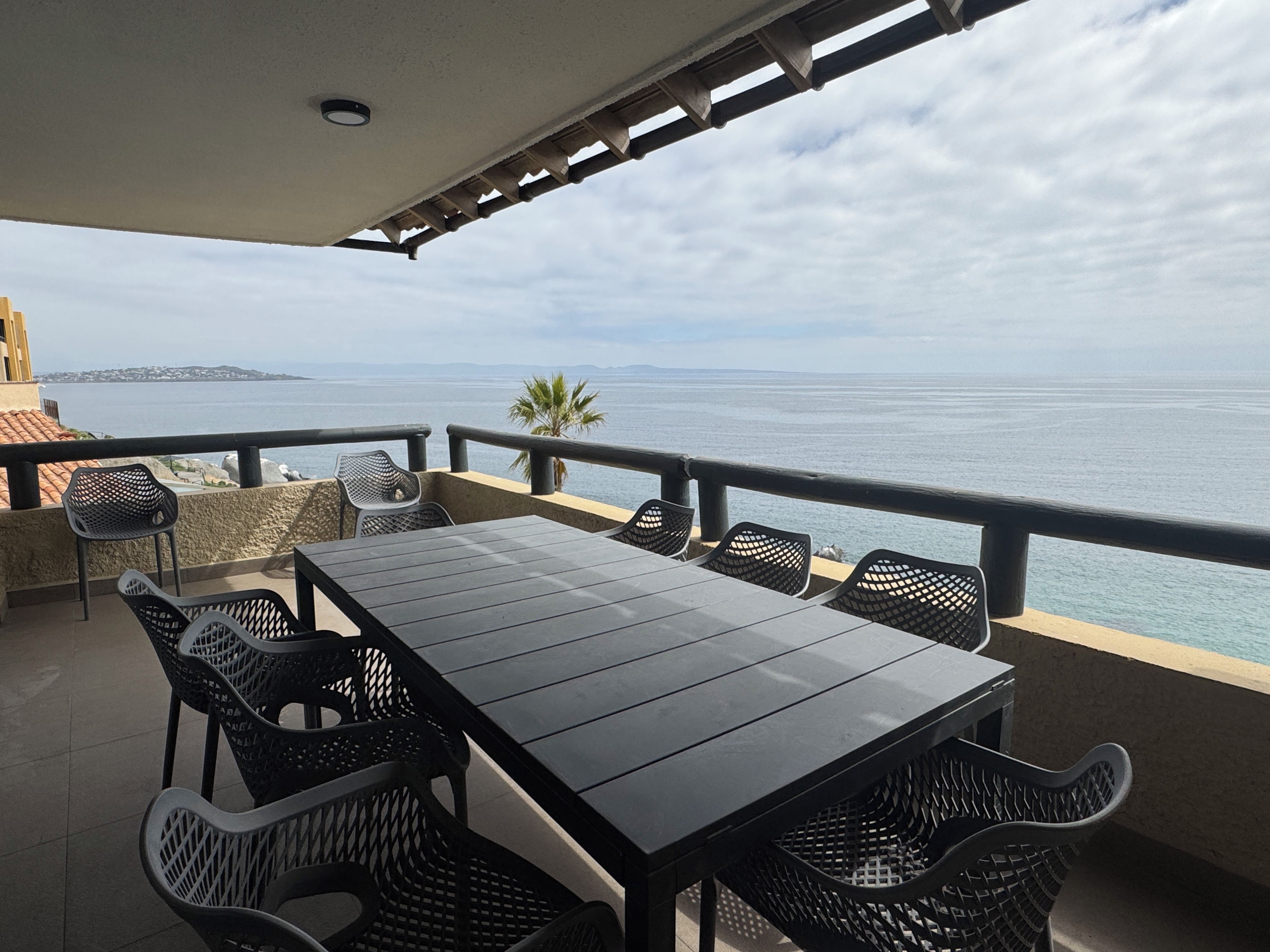 An outdoor terrace with a table and chairs, overlooking a body of water and a distant coastline.