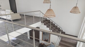 A modern interior with a staircase, metal railings, and wicker pendant lighting. - Hermosa casa de mar (Escuintla)