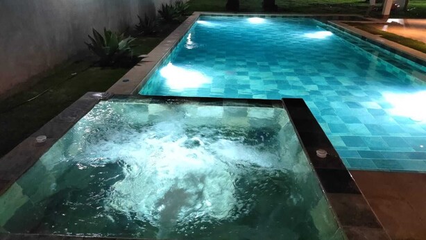 A rectangular pool with a checkered pattern and a separate hot tub area with visible water jets. - Hermosa casa de mar (Escuintla)