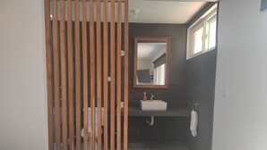 A modern bathroom with a wooden partition, a white sink, a mirror, and a towel on the floor. - Hermosa casa de mar (Escuintla)