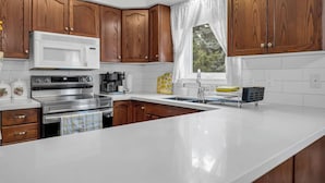 A modern kitchen with wooden cabinets, stainless steel appliances, and a white countertop. - Sunflower Manor; Your Wine Country Family Retreat (Niagara-on-the-Lake)