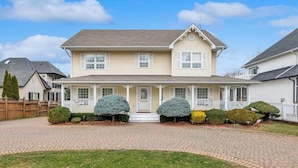 A two-story house with a front porch, a brick driveway, and a well-maintained lawn. - Sunflower Manor; Your Wine Country Family Retreat (Niagara-on-the-Lake)