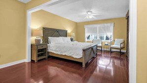 A bedroom with a bed, nightstands, a chair, and a window with curtains. - Sunflower Manor; Your Wine Country Family Retreat (Niagara-on-the-Lake)