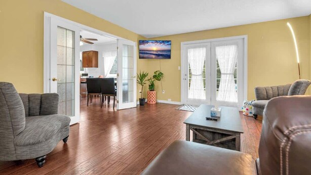 A living room with a sofa, a coffee table, and a TV mounted on the wall. - Sunflower Manor; Your Wine Country Family Retreat (Niagara-on-the-Lake)
