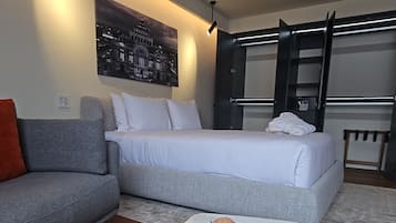 Habitación de hotel moderna con sofá, cama, mesita de centro de mármol y un cuadro en la pared.