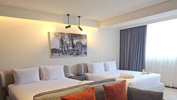 A hotel room with a large bed, a sofa, and a painting on the wall.