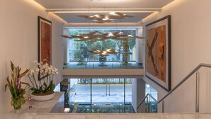 A modern interior with a glass staircase, a ceiling with circular light fixtures, and artwork on the walls. - Amberes 64, an Ascend Collection Hotel (Mexico City)
