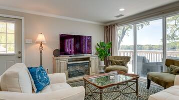 Una sala de estar con chimenea, televisor y vistas al exterior.