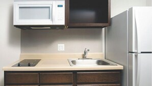 A compact kitchen with a microwave, stove, sink, and refrigerator. - Woodspring Suites Rochester Greece (Rochester)