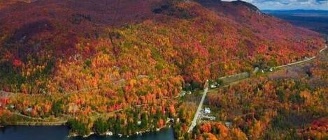A mountainous landscape with autumn foliage, a lake, and a road.