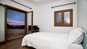 Un dormitorio con una cama, un ventanal y vistas al cielo.