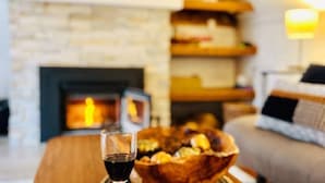 Una sala de estar acogedora con chimenea, una mesa de centro con una copa de vino tinto y un bol de aperitivos.