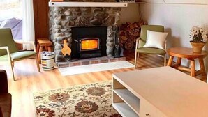 A cozy living room with a stone fireplace, wooden ceiling, and a patterned rug. - The Rustic (Mont-Orford) (Orford)