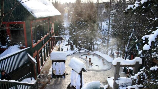 A snow-covered outdoor area with a wooden deck, a hot tub, and a wooden structure with benches. - The Rustic (Mont-Orford) (Orford)