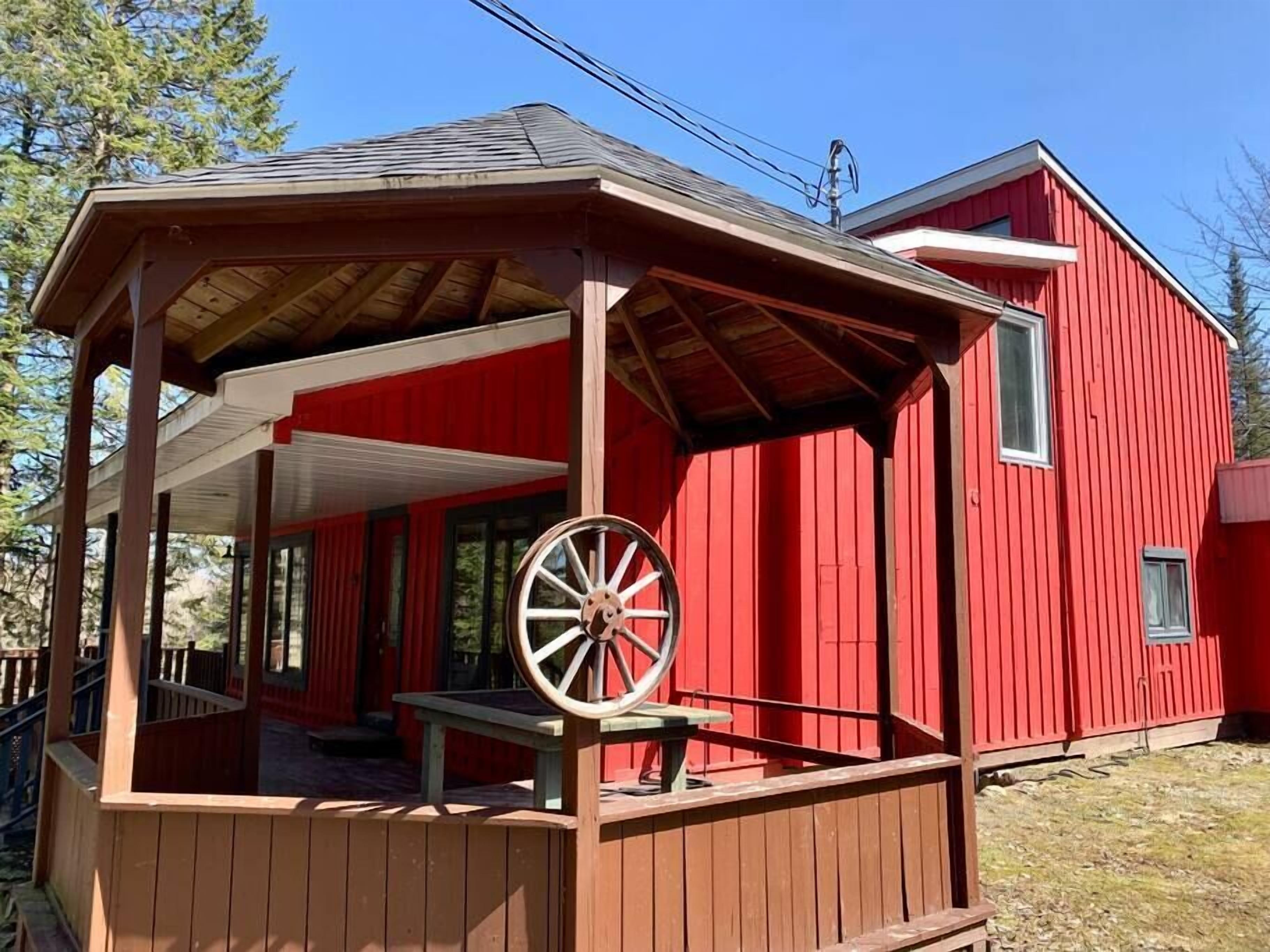 A red wooden building with a covered porch and a large wooden wheel.
