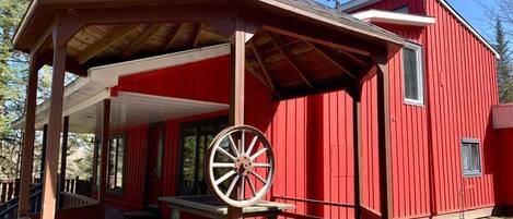 A red wooden building with a covered porch and a large wooden wheel.