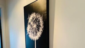 Un mueble de madera con una obra de arte de diente de león en blanco y negro encima.