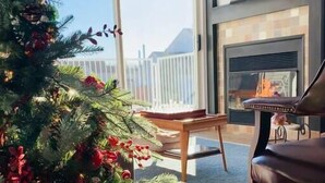 Una sala de estar moderna con chimenea, un árbol de Navidad y un balcón con vistas.