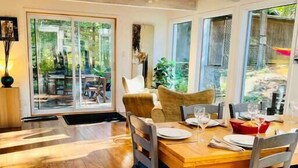 Un comedor con mesa y sillas de madera, ventanas amplias y vistas al exterior.