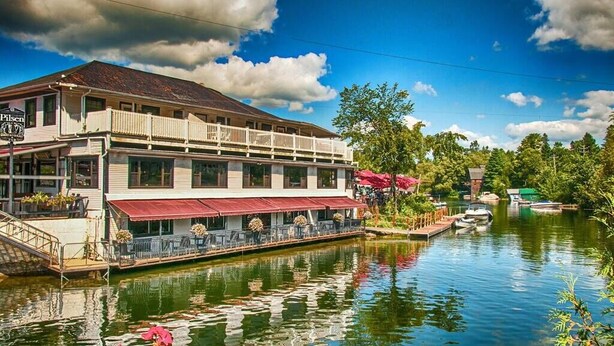 Un edificio junto al río con balcón y zona de estar al aire libre.