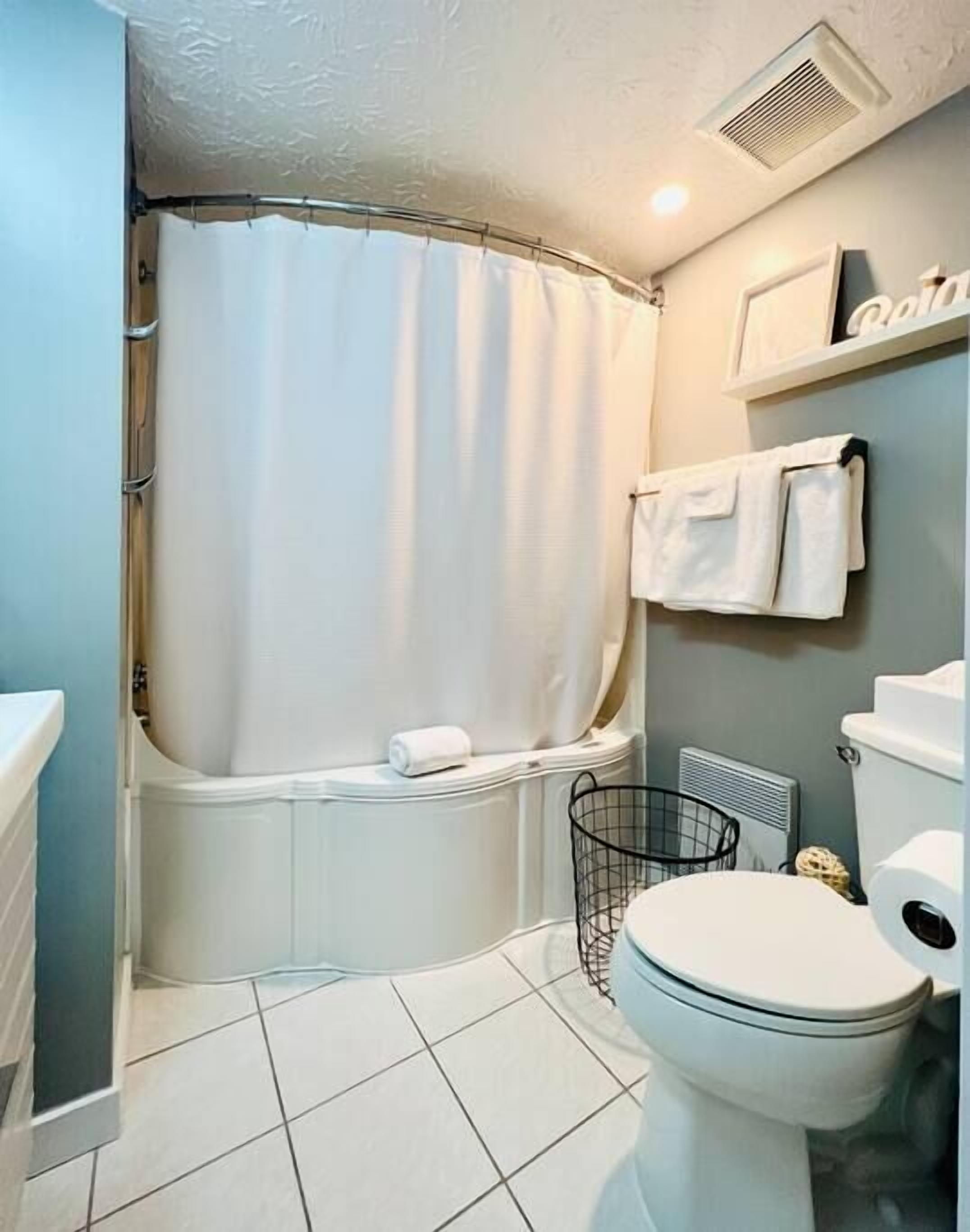 A bathroom with a bathtub, toilet, and a shower curtain.