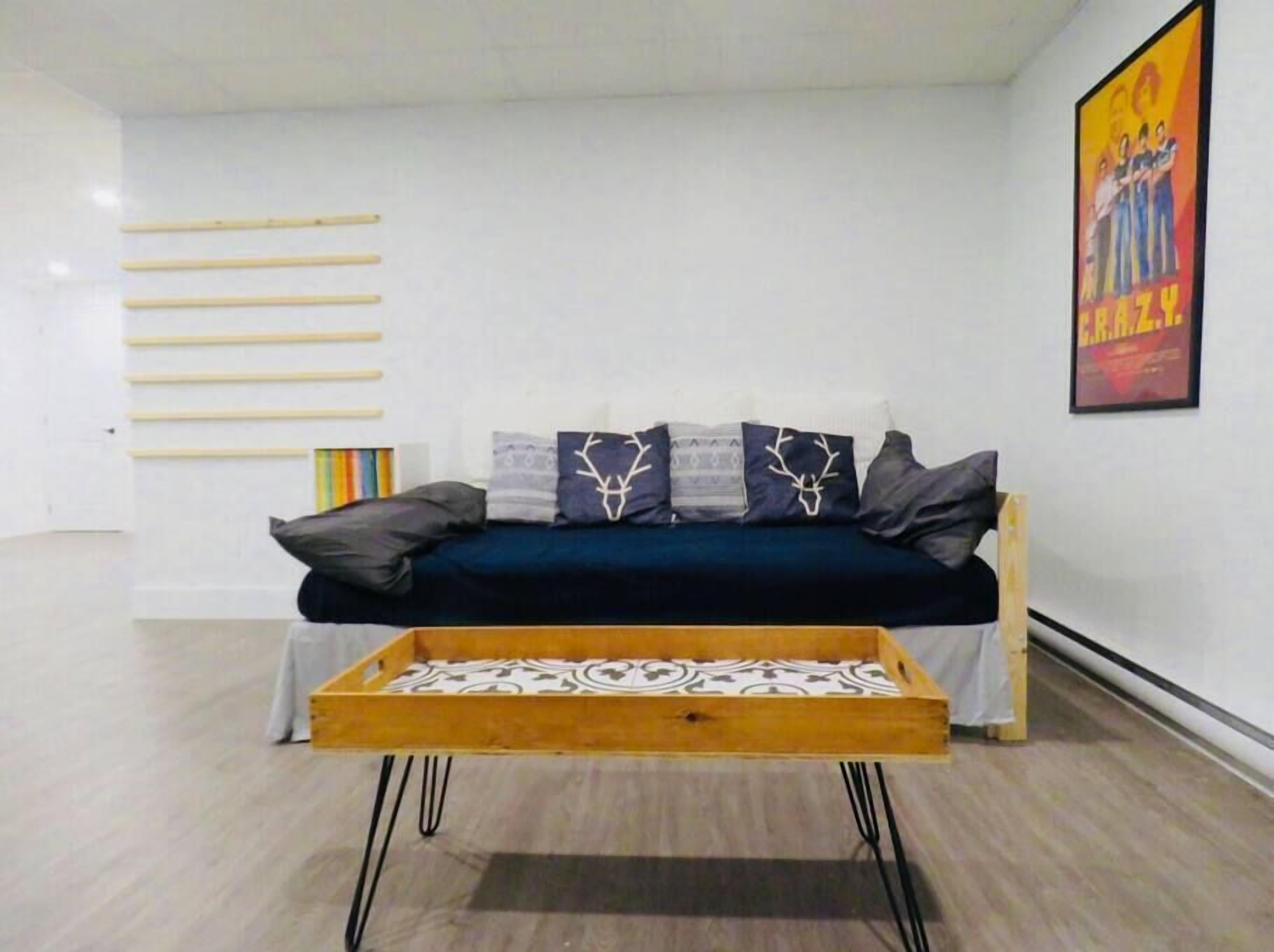 Ein modernes Wohnzimmer mit einer Couch, Zierkissen, einem Holztisch und einem Poster an der Wand.