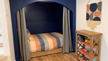 Une pièce chaleureuse avec un lit placé sous un plafond cintré, une bibliothèque en bois et une décoration murale en macramé.