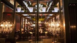 A restaurant with multiple dining tables and chairs, a chandelier, and potted plants on shelves. - The Surf N Turf-Spa-Eastman-Lake Access (Eastman)