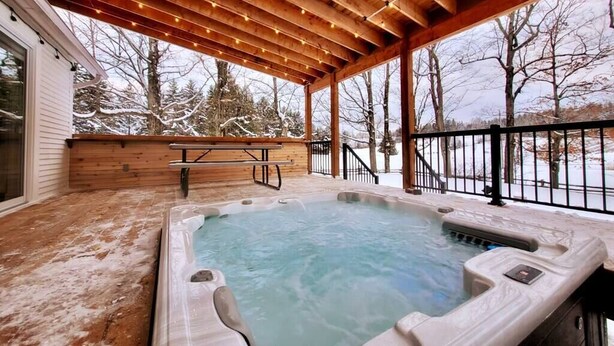 Een hottub op een houten terras, met uitzicht op een besneeuwd landschap.