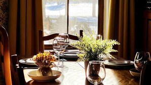 Een eettafel gedekt met borden, glazen en een vaas met een plant.