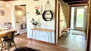 A modern kitchen with white cabinets, a dining area with a wooden table and chairs, and a large window providing natural light. - Le Refuge-Orford 6 PeopleSEPAQ (Orford)