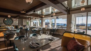 A spacious restaurant with high ceilings, large windows, and a view of the outdoors. Tables are set with wine glasses and plates. - Le Refuge-Orford 6 PeopleSEPAQ (Orford)