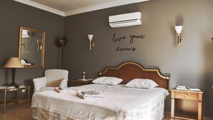 A neatly arranged bedroom with a bed, bedside tables, a chair, and a wall-mounted air conditioner. - Villa Nordic Dream (Kas)
