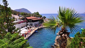A coastal hotel with a poolside area, a mountain in the background, and a clear view of the sea. - Villa Nordic Dream (Kas)