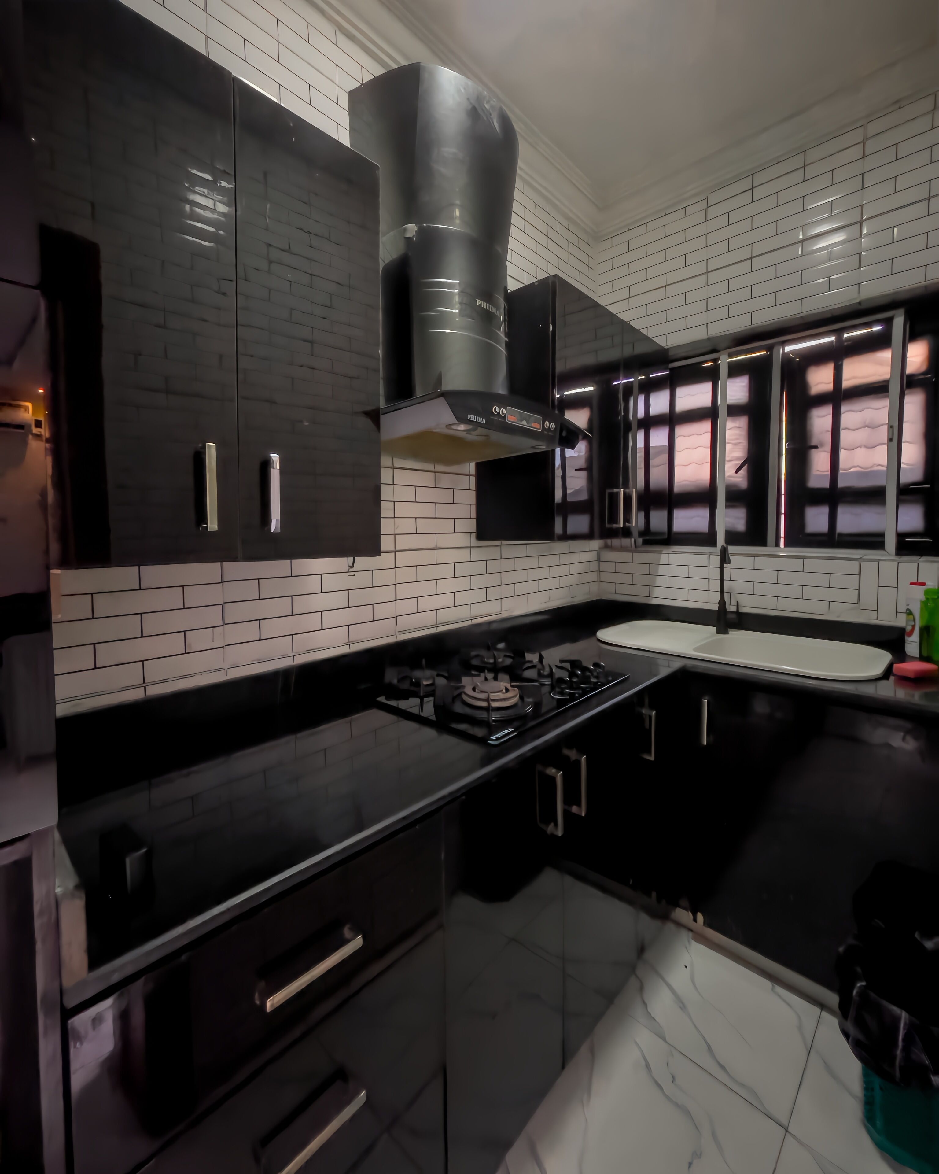 A modern kitchen with black cabinets, a gas stove, and a stainless steel range hood.