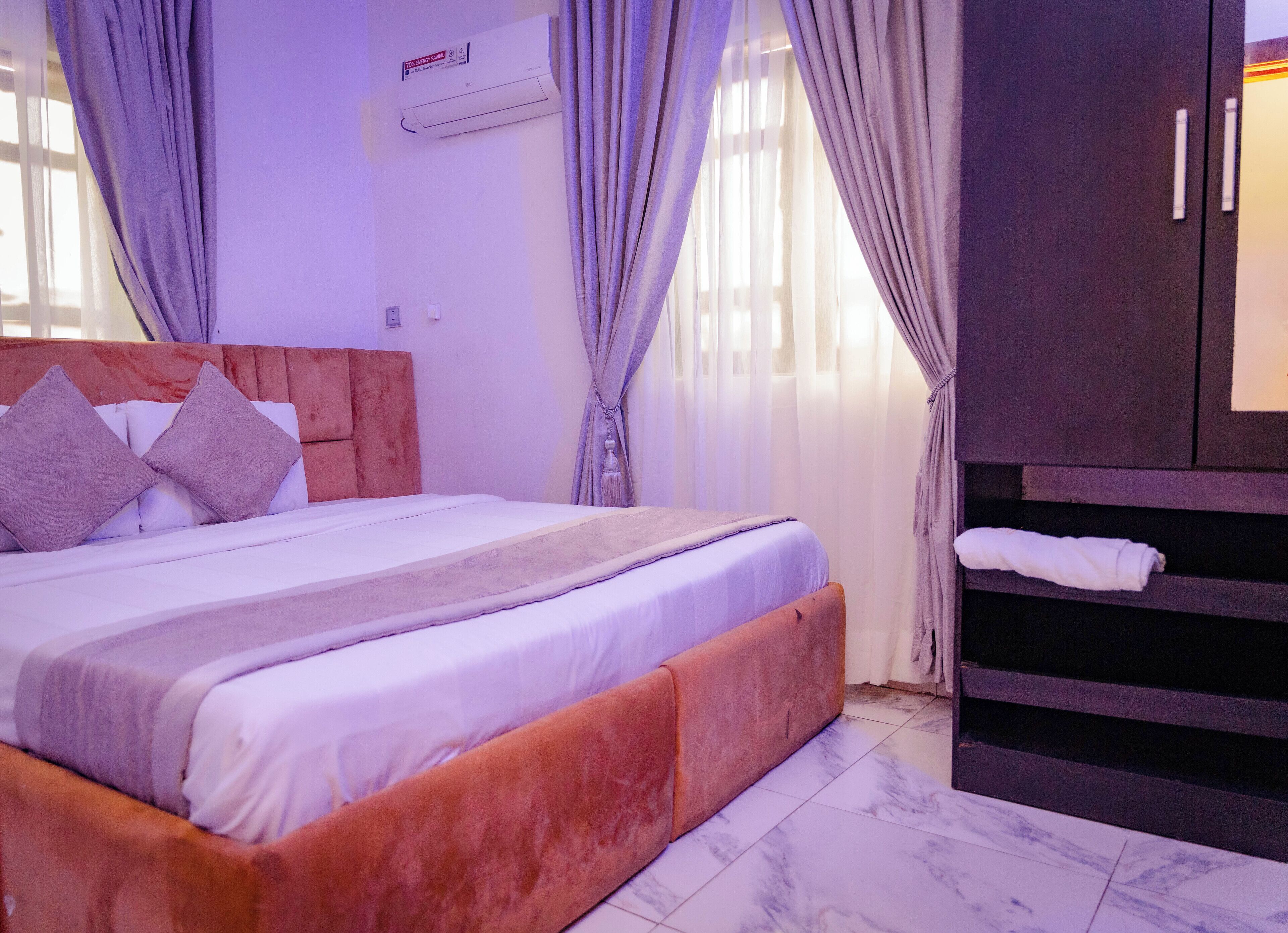 Een slaapkamer met een bed, gordijnen, een airconditioner en een kledingkast.
