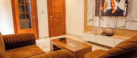 A living room with a wooden door, a television mounted on the wall, a sofa, and a coffee table.