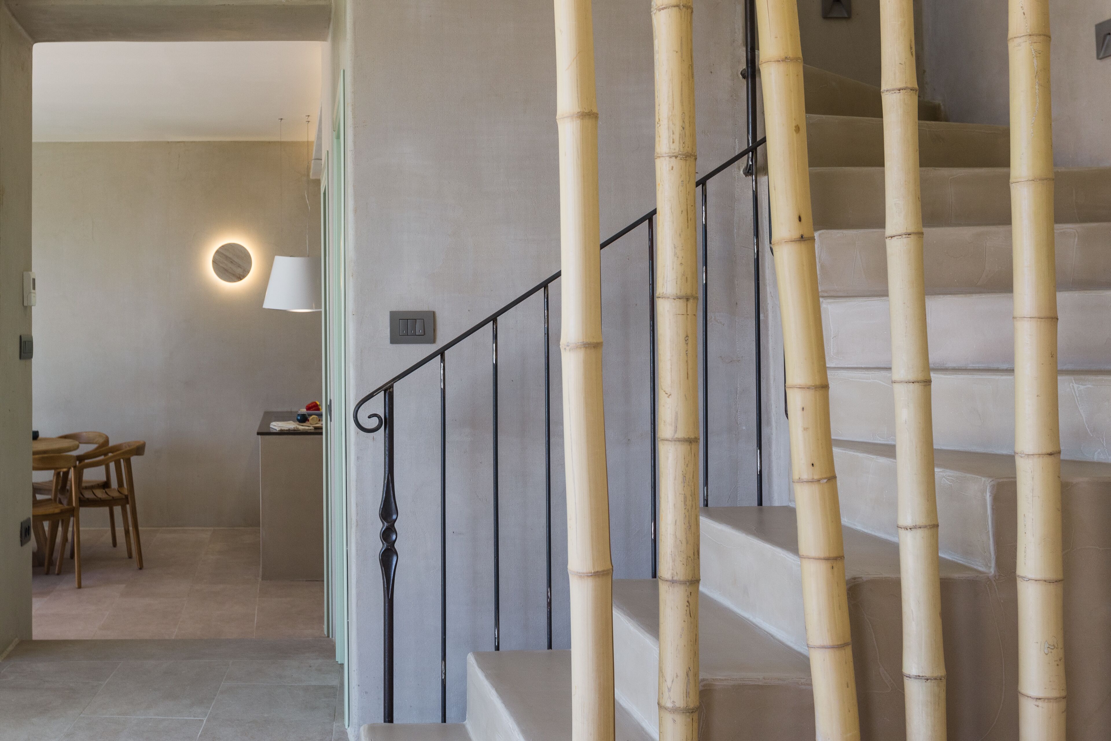 A staircase with bamboo balusters and a modern light fixture on the wall.