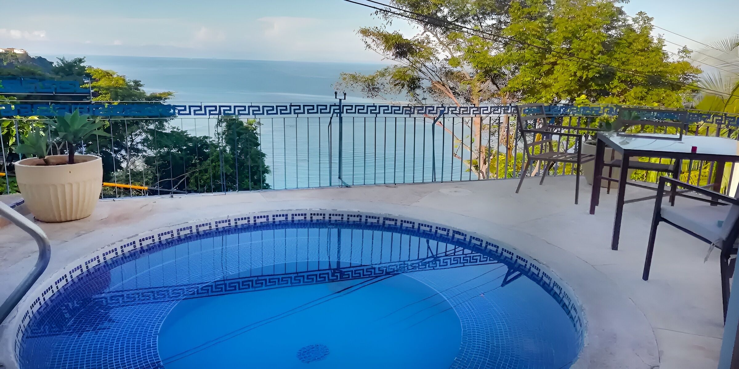 Piscina com vista para o mar, rodeada por uma vedação com padrão decorativo.