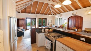 Una cocina amplia con una isla central, horno empotrado y refrigerador. Hay un comedor con una mesa y sillas de madera.