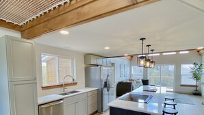 A modern kitchen with a central island, stainless steel appliances, and a wooden ceiling.