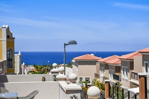 A coastal residential area with buildings, a street lamp, and a view of the ocean.