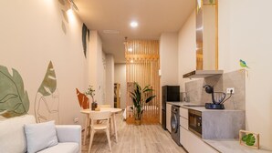Una sala de estar moderna con un sofá, una mesa de comedor y una zona de cocina con electrodomésticos.
