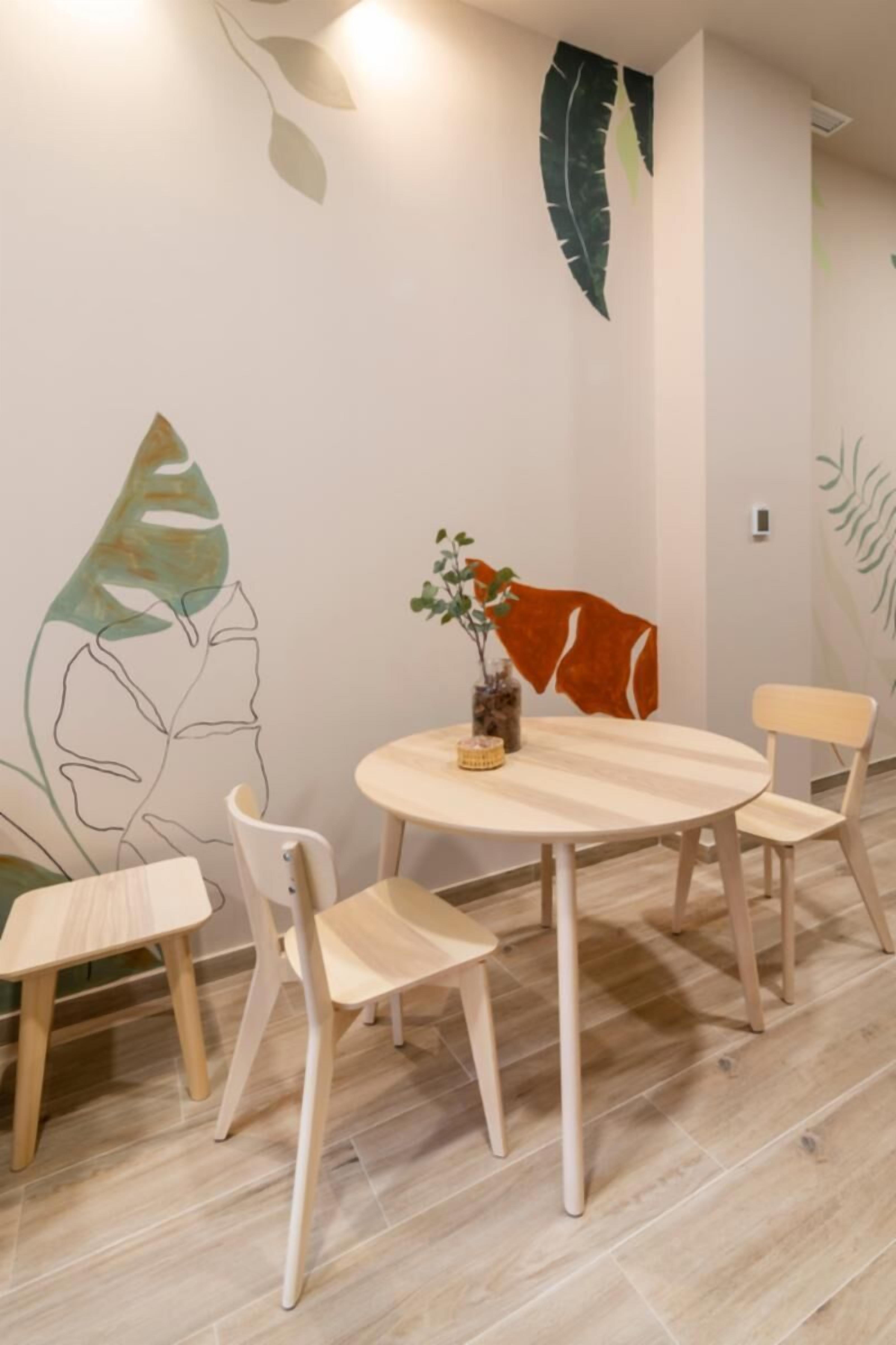 Een eetgedeelte met een ronde tafel, vier stoelen en een vaas met een plant.