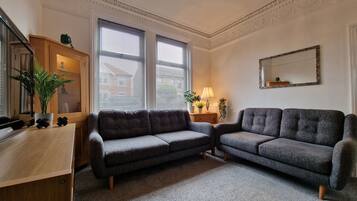 Relax in this stylish living room with a large sofa, desk, and potted plants.