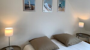 A bedroom with a bed, two bedside lamps, and three framed pictures on the wall. - Charming villa - beaches 5 minutes away (Carolles)