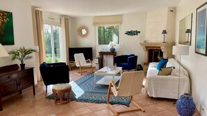 A living room with a sofa, chairs, a coffee table, a fireplace, and a large window. - Charming villa - beaches 5 minutes away (Carolles)