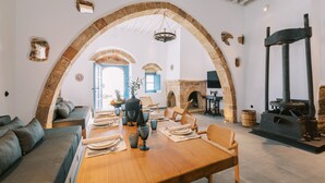 Un comedor con una mesa de madera dispuesta para cuatro personas, arcos de piedra, una chimenea y una pared de piedra.