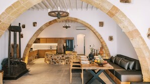Un interior con un arco de piedra, una mesa de madera, un sofá y una chimenea de piedra.